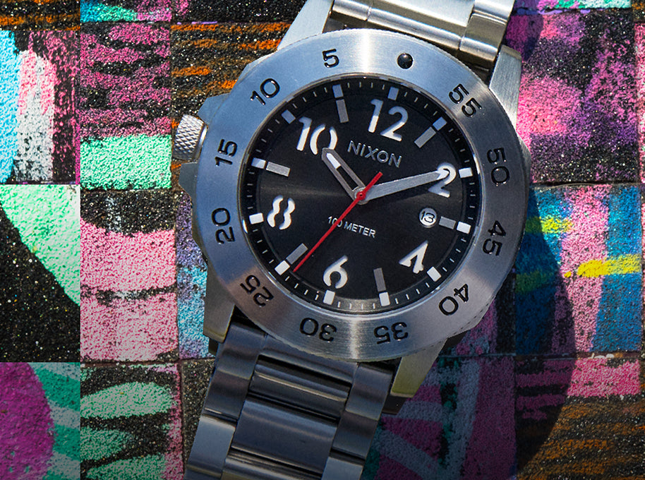 Nixon Smyth 44 analog watch in silver on a colorful backdrop