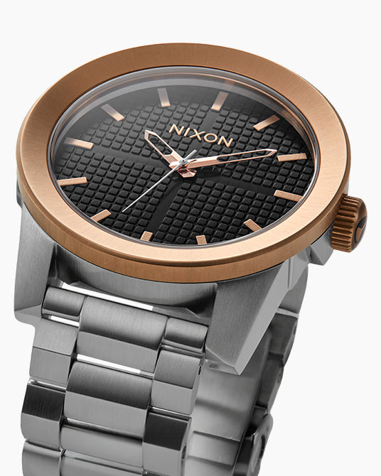 Nixon watch with bronze bezel and silver band on a white background